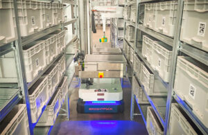 a brightpick autopicker in a tight warehouse aisle pulls pharma items from totes.