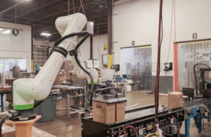 A Formic-branded cobot picking up two boxes from a conveyor belt.