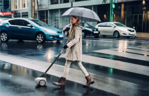 a blind woman crossing the street in a crosswalk, guided by Glidance device