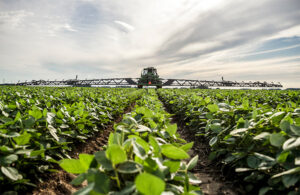 john deere tractor equipped with a sprayer boom on each side of the tractor, in field.