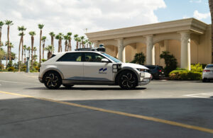 A Motional robotaxi in front of a building with columns and palm trees in Las Vegas.